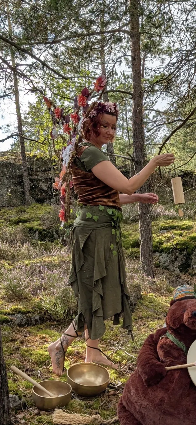 Keiju Aarnitar soittaa puista tuulikelloa männikössä